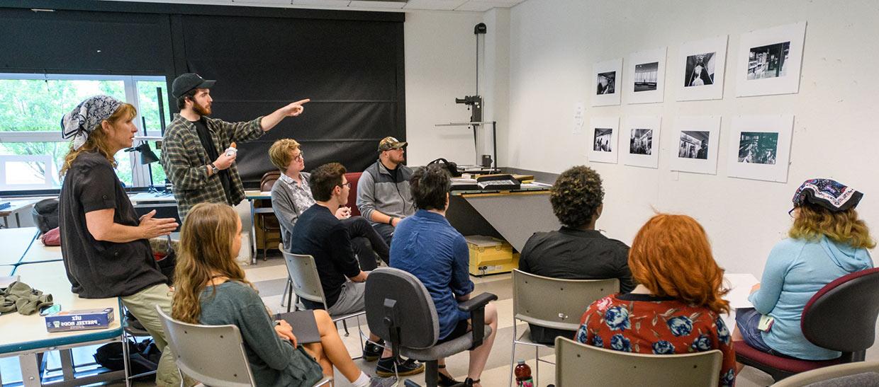 Students and their professor reviewing art projects